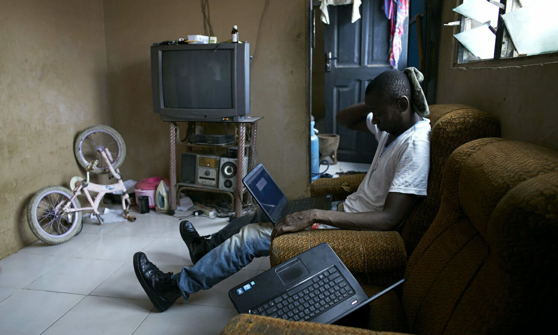 A romance scammer known as “Ghost” works on his laptop in a house on April 19, 2015 in Zongo area of Accra, Ghana.  He is one of many young unemployed men here who is involved in internet scams(Per-Anders Pettersson)