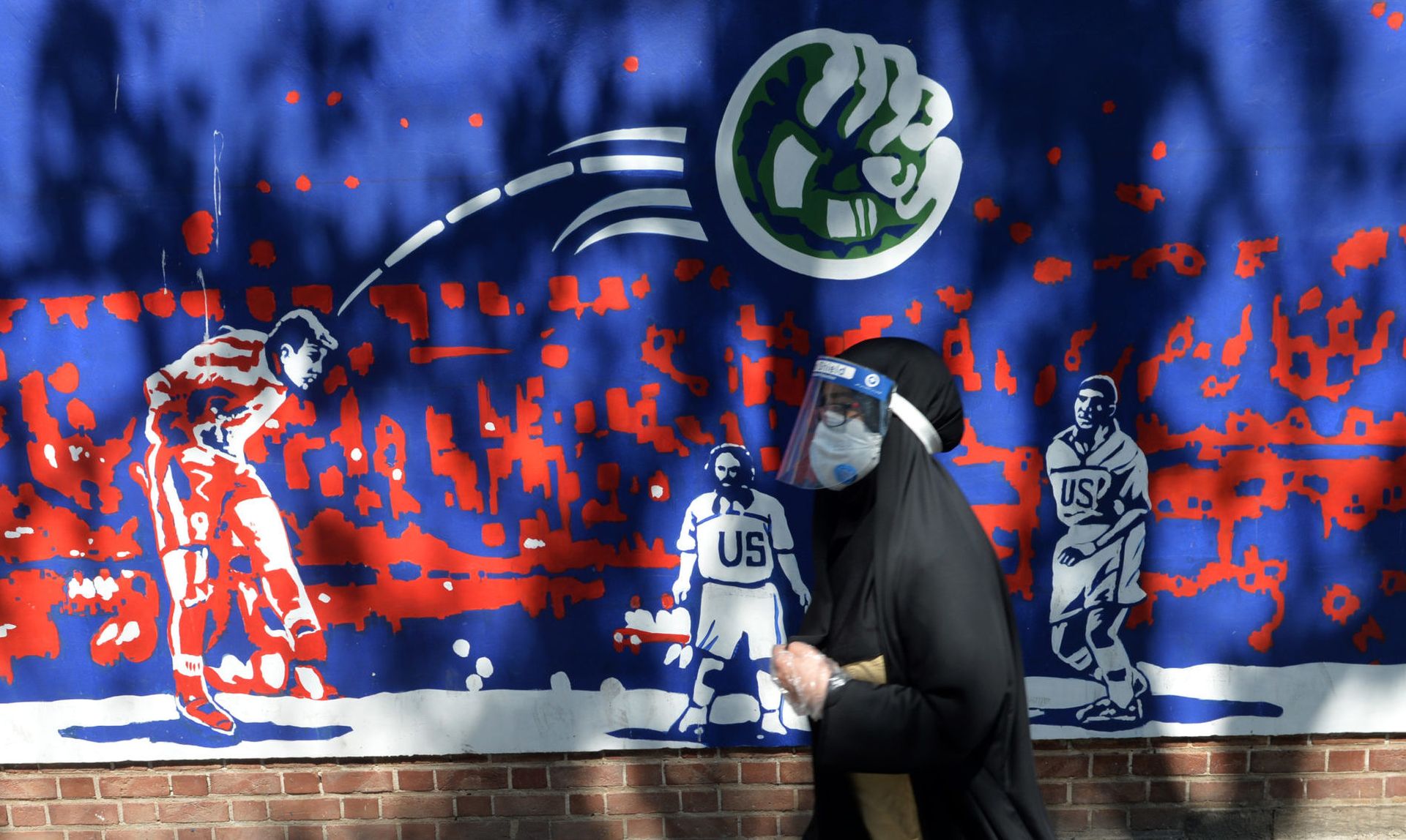 A woman, wearing a face mask and a shield as a preventive measure against the coronavirus, walks past a mural as daily life continues in the country after U.S. administration reimposed sanctions on Iran Sept. 21, 2020. (Fatemeh Bahrami/Anadolu Agency via Getty Images)