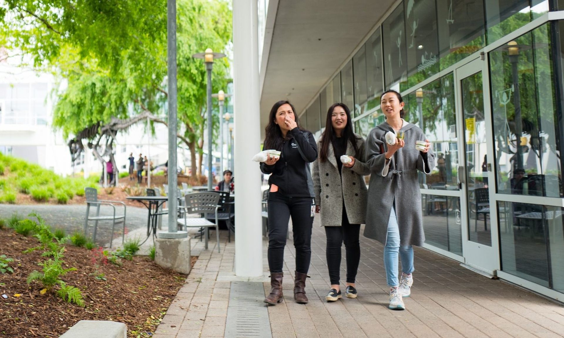 Three young, millennial age female tech workers walk and hold lunch foods at the Googleplex, headquarters of Google Inc in the Silicon Valley town of Mountain View, California, April 7, 2017. (Smith Collection/Gado/Getty Images).