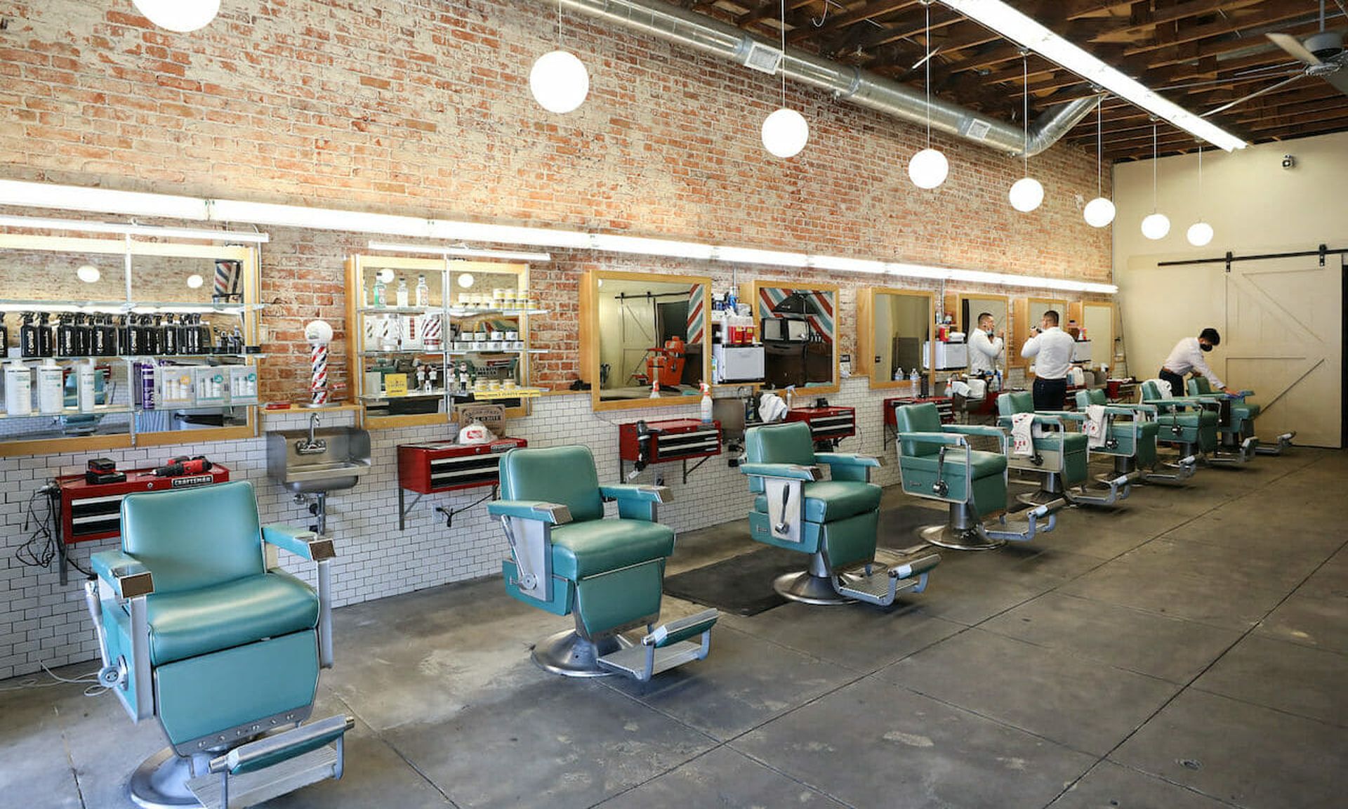 Workers gather in a California barbershop in July, closing amid new restrictions due to the COVID-19 pandemic. The city of Sacramento launched a workforce training program to recruit individuals that lost their jobs from pandemic fallout to cybersecurity. (Photo by Mario Tama/Getty Images)