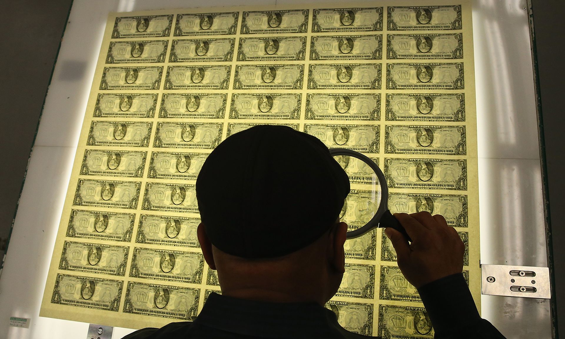 Pictured: A printing supervisor inspects sheets of one dollar bills run through the printing press at the Bureau of Engraving and Printing on March 24, 2015, in Washington. (Photo by Mark Wilson/Getty Images)