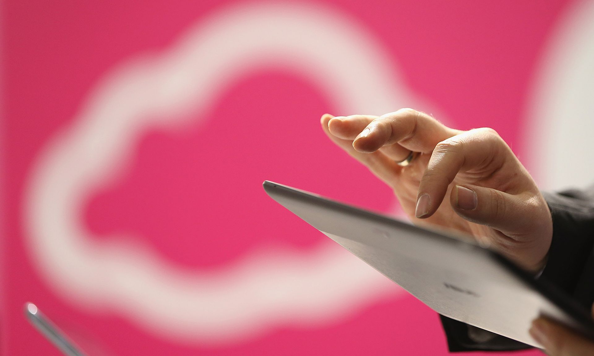 Executives are valuable — and vulnerable — targets to threat actors, a BlackCloak survey found. Pictured: A visitor uses a tablet computer next to a cloud computing symbol at the 2013 CeBIT technology trade fair on March 5, 2013, in Hanover, Germany. (Photo by Sean Gallup/Getty Images)