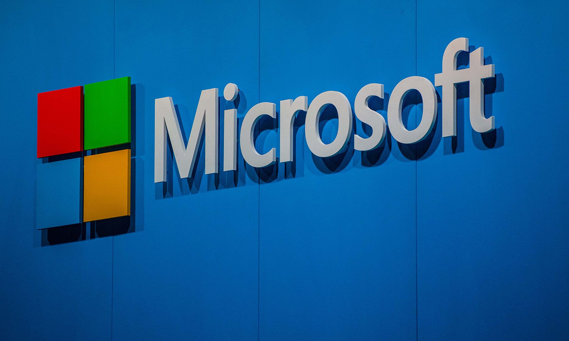 The four-color Microsoft logo is displayed on a blue wall.