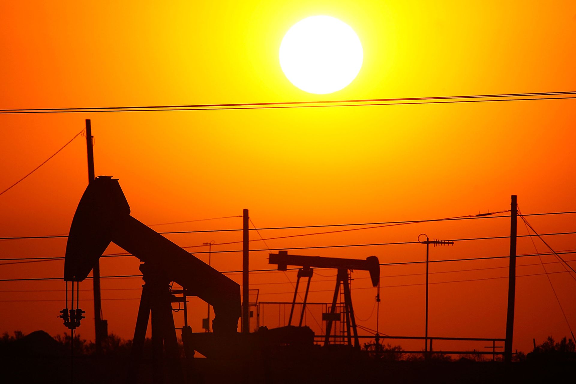 Oil rigs extract crude at sunrise.