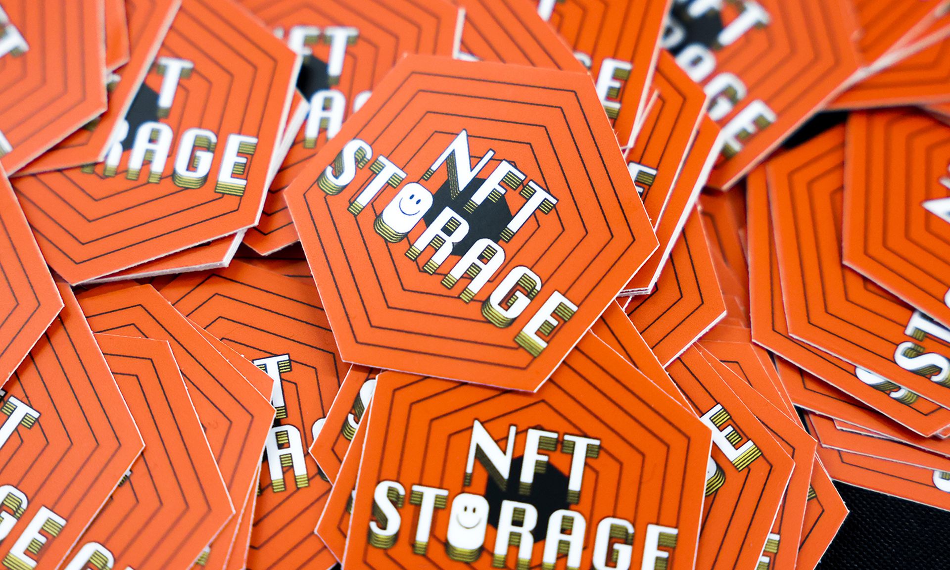 Orange stickers with the words "NFT storage" written in white sit in a pile.