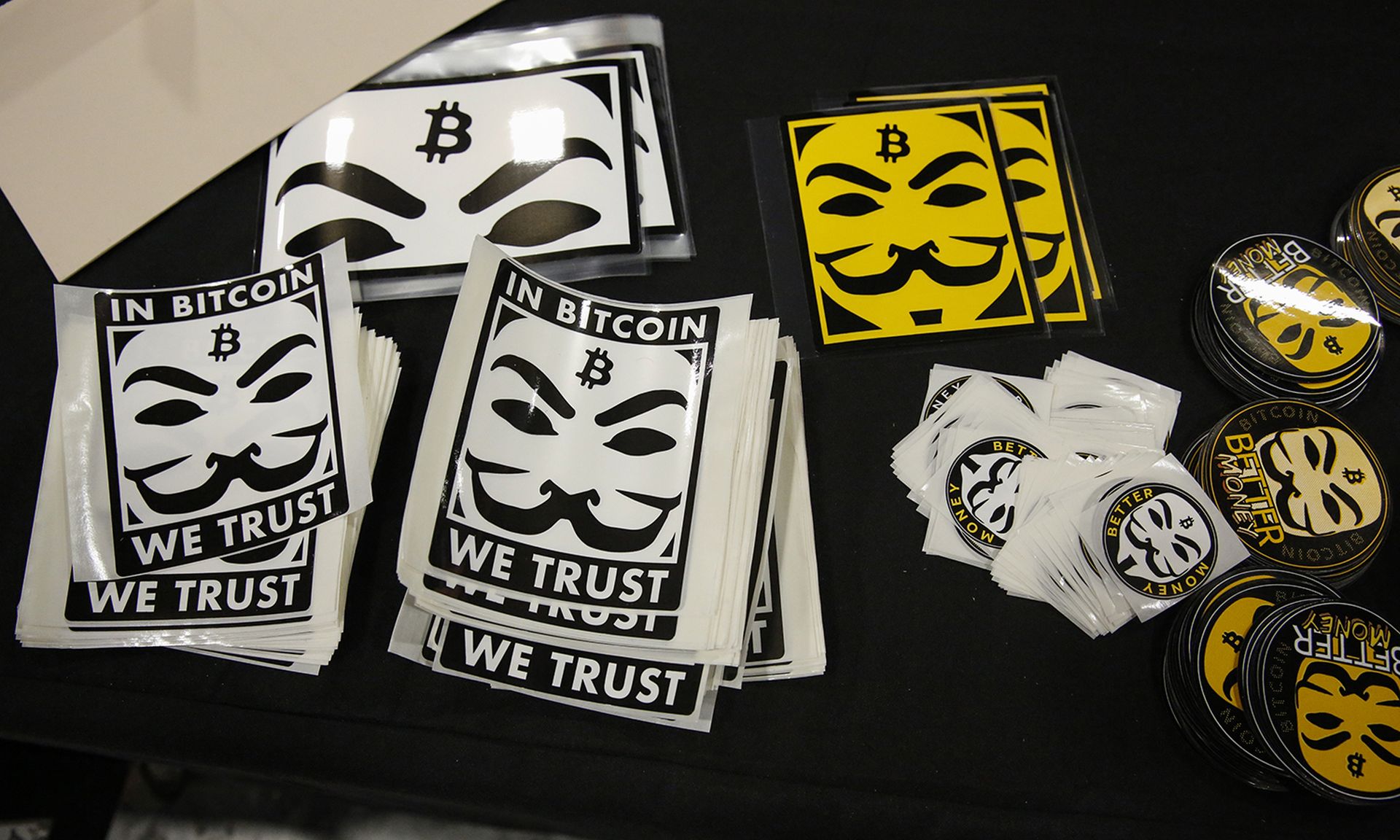 Stickers depicting Guy Fawkes masks (Anonymous mask) and the bitcoin logo are seen at a stand