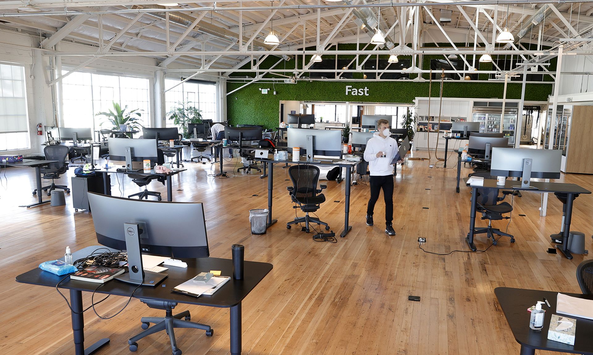 An employee walks among desks in an empty office.