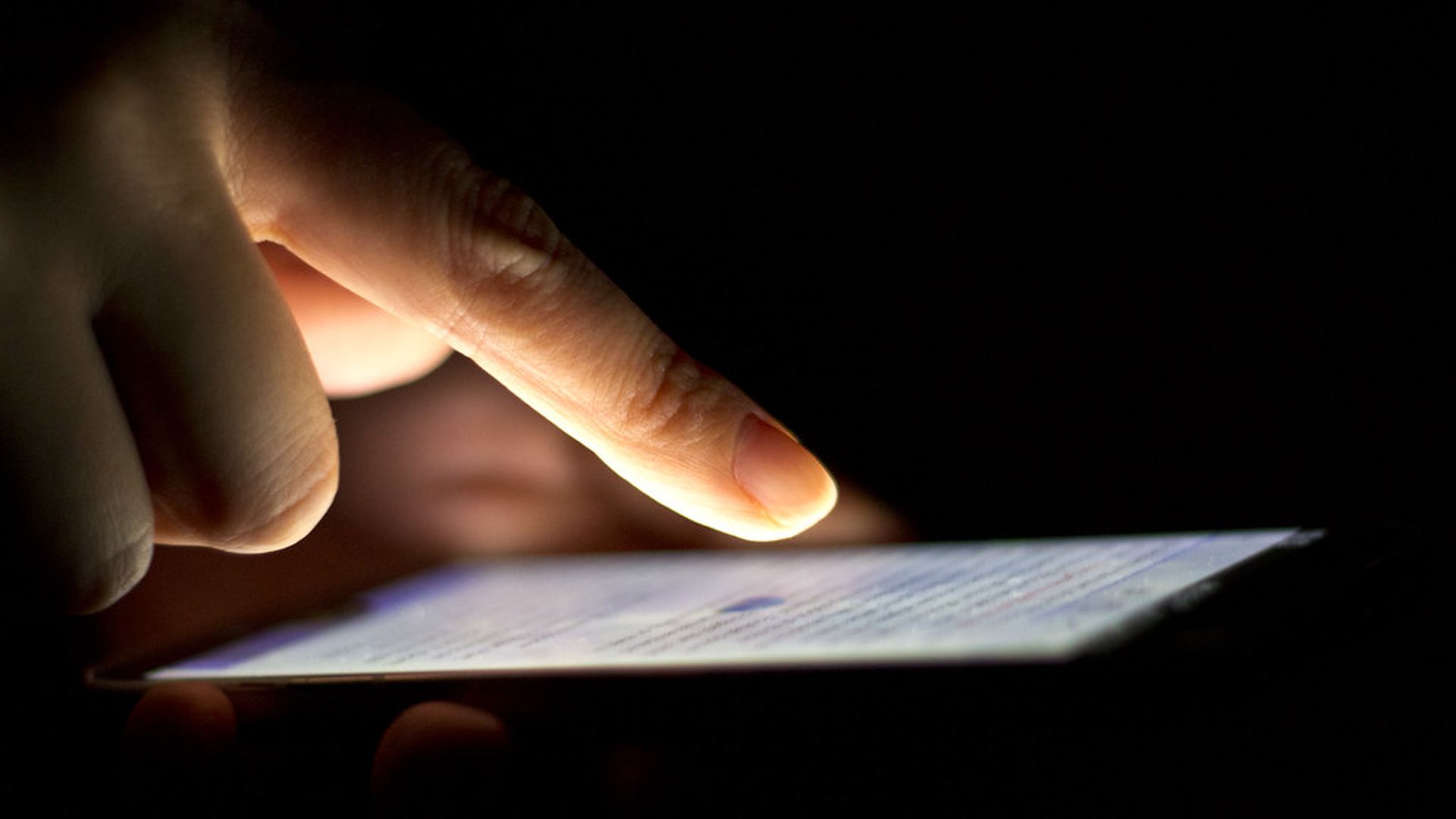 A person's finger hovers over the touchscreen of a smartdevice.