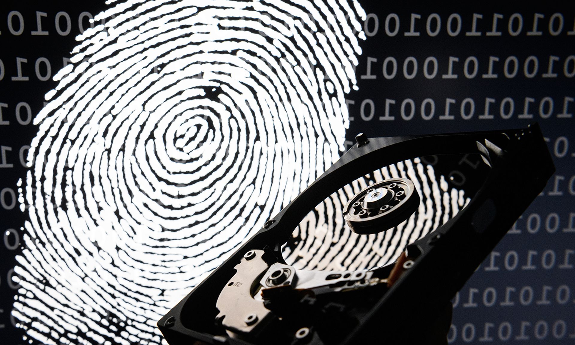 A hard drive is seen in the light of a projection of a thumbprint.