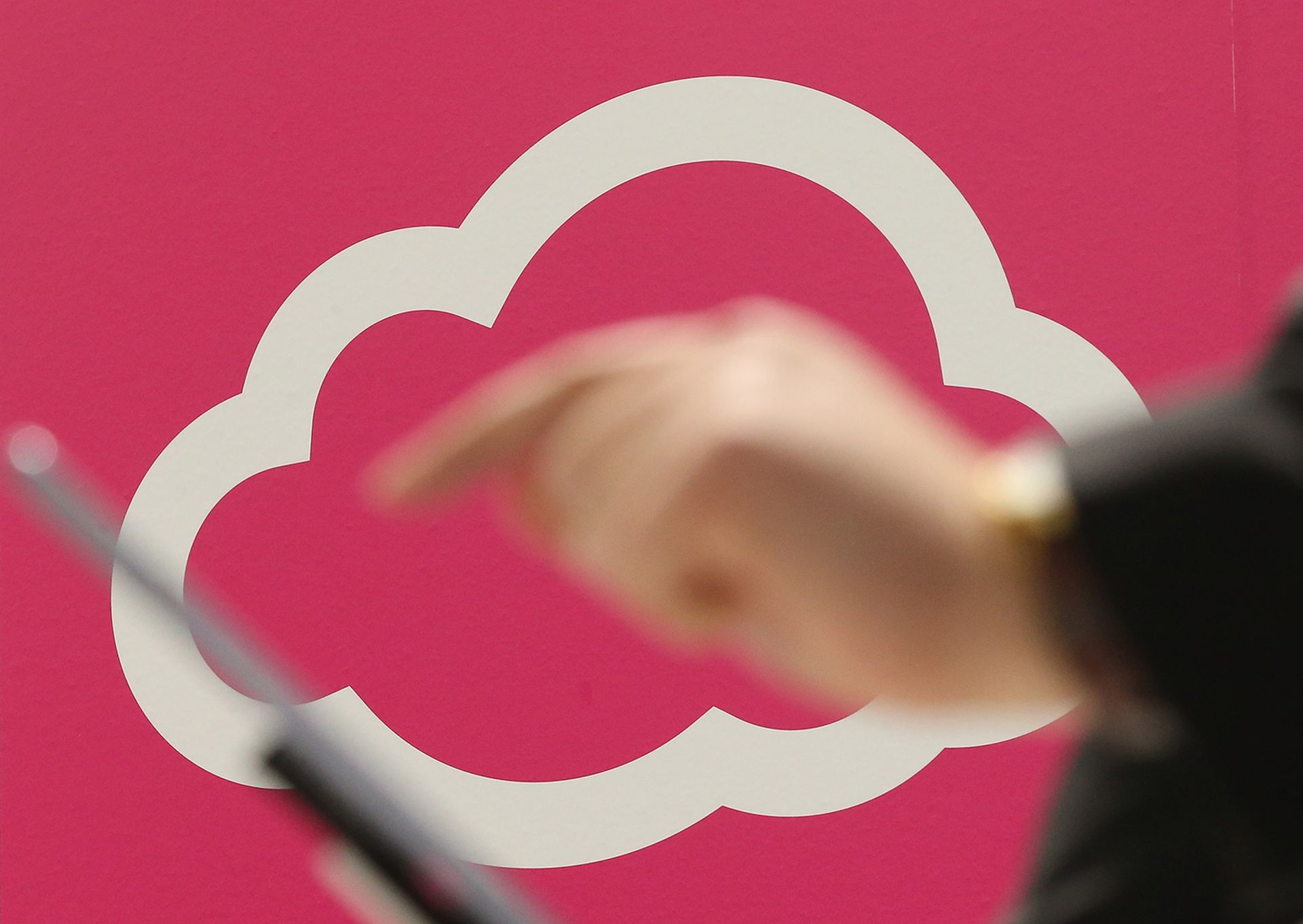 A visitor tries out a tablet computer next to a cloud computing and technology symbol.