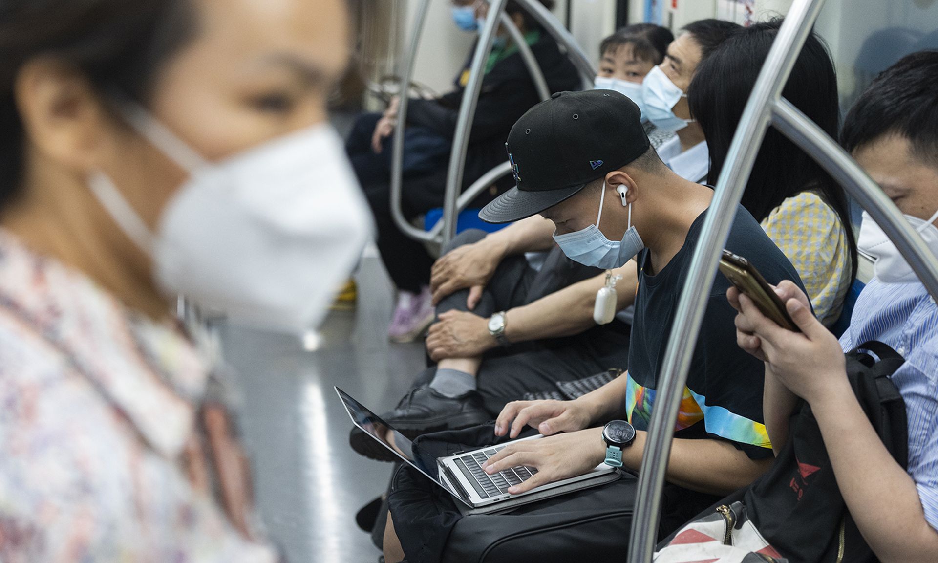 A man works with his laptop at subway car.