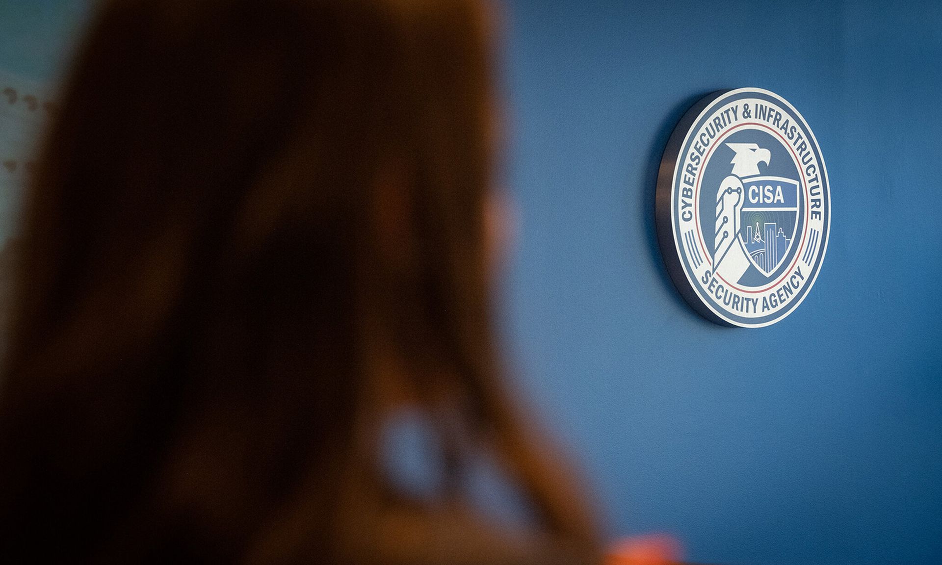 The CISA logo is seen hanging on a blue wall