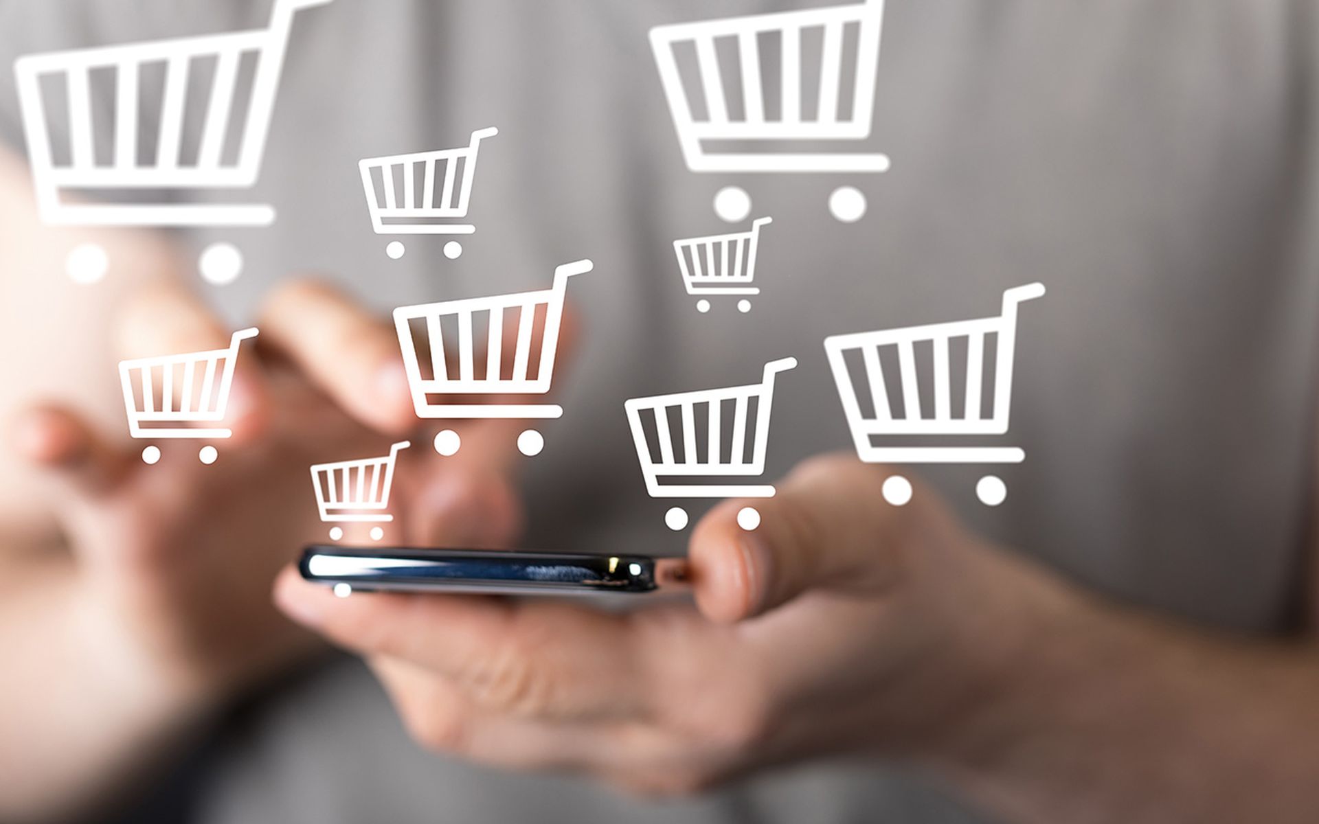 A man holds a smartphone with checkout icons floating around