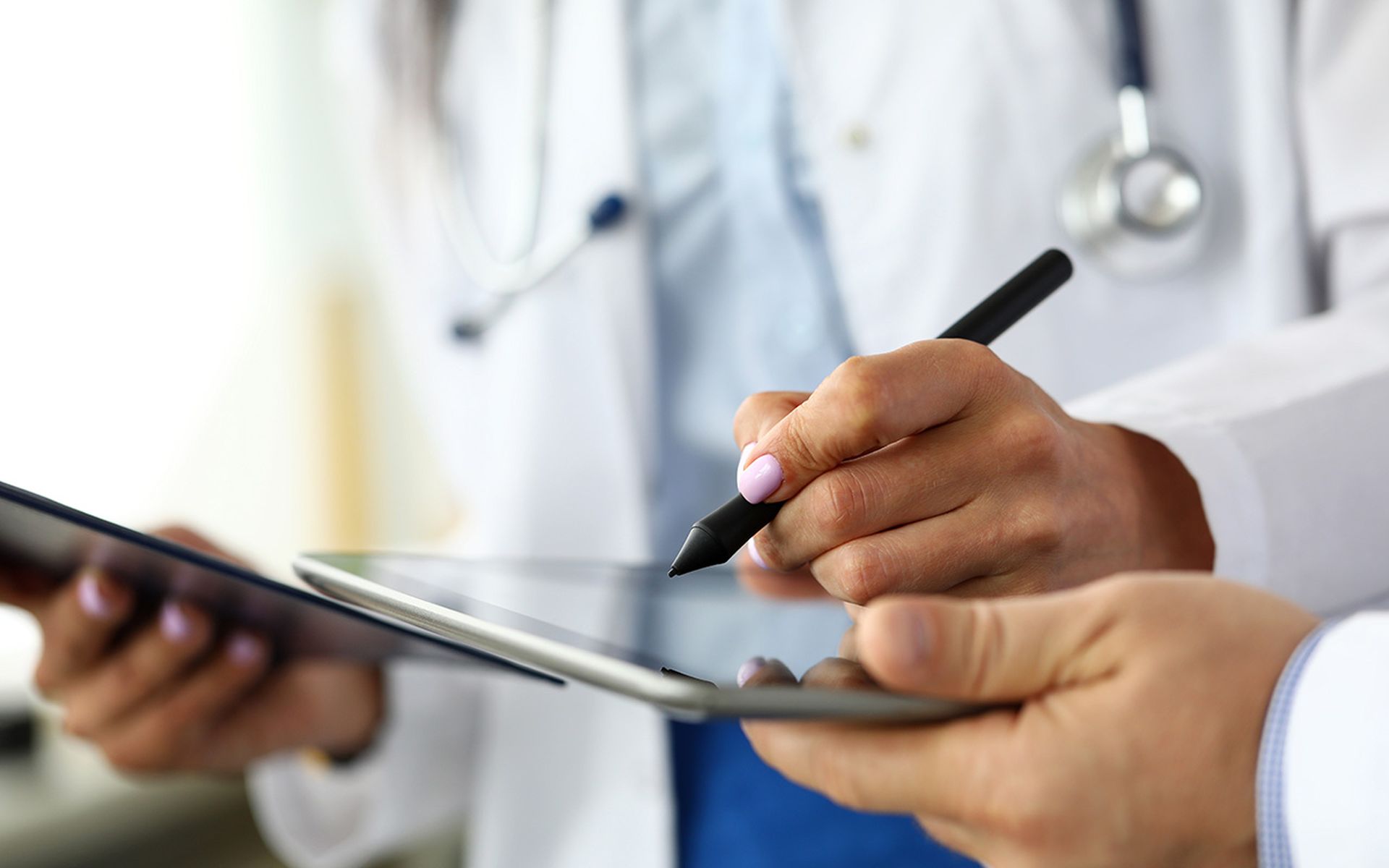 A healthcare worker makes electronic notes on a tablet.
