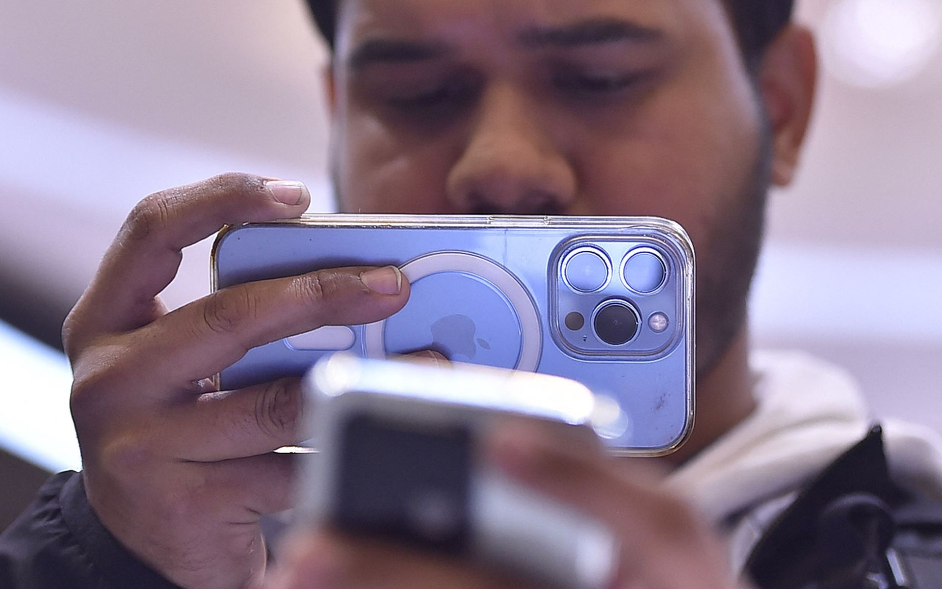 A man takes a photo with an Apple iPhone.