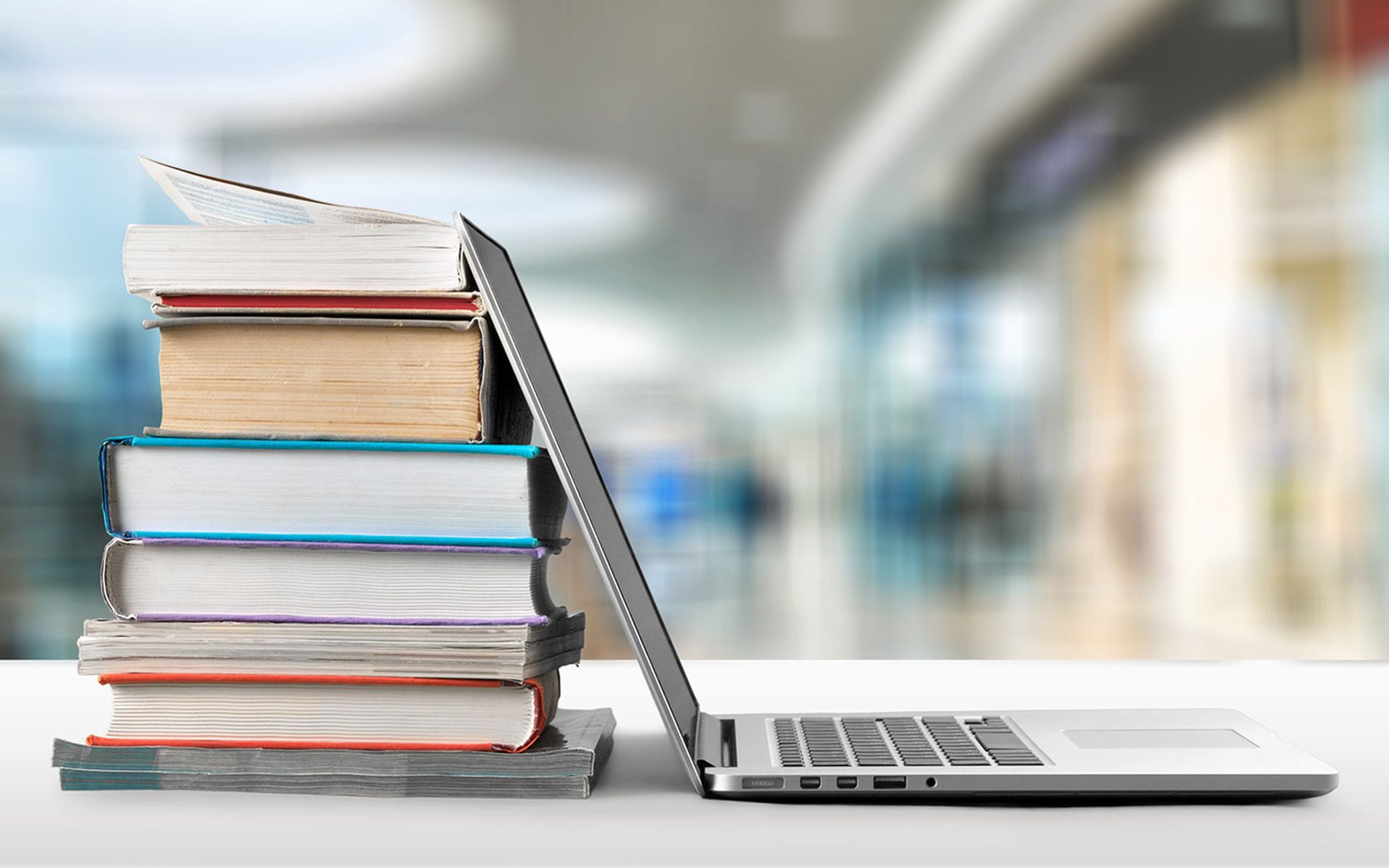 Stack of books with laptop on wooden table