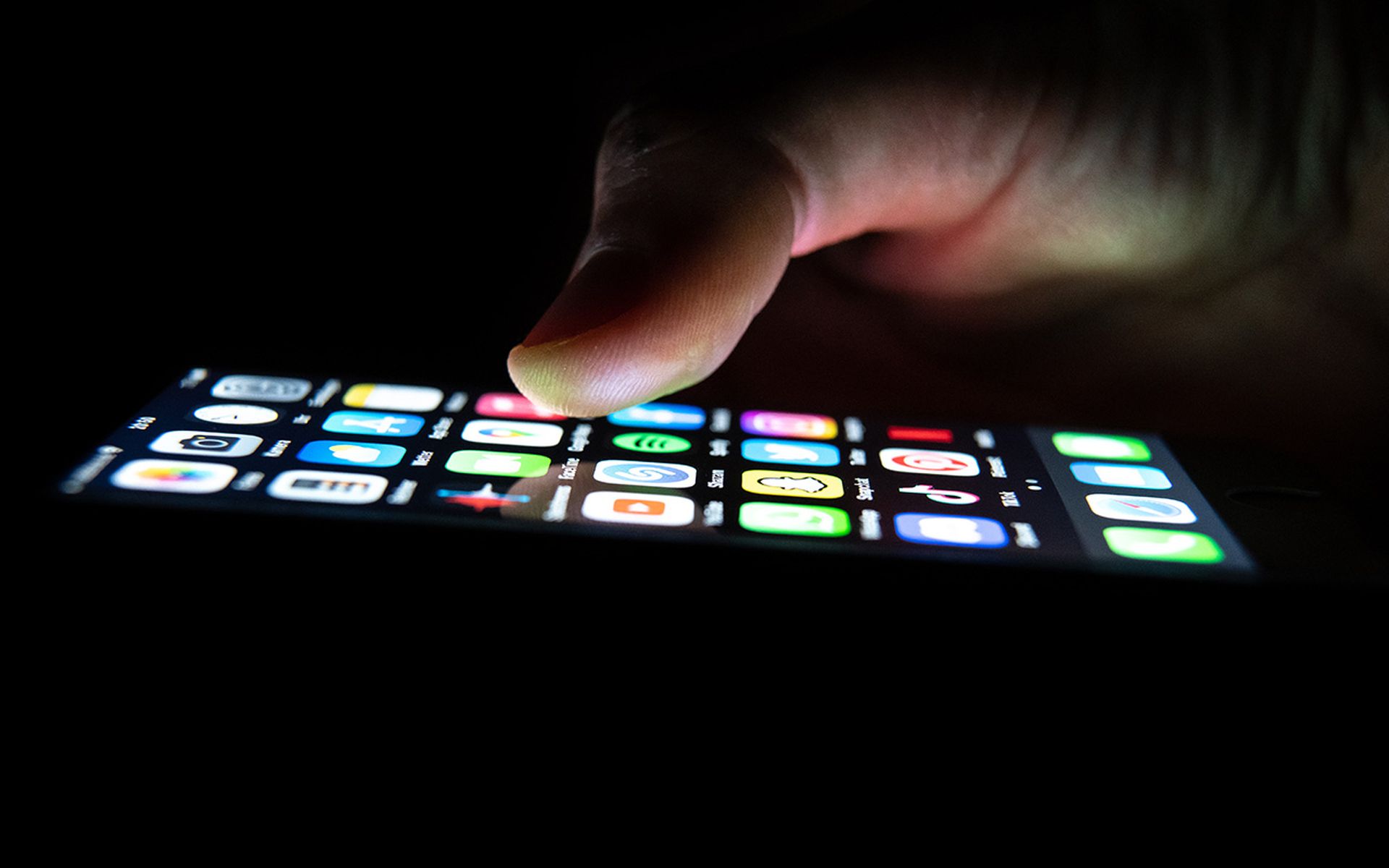 Closeup of a hand using an iPhone in the dark