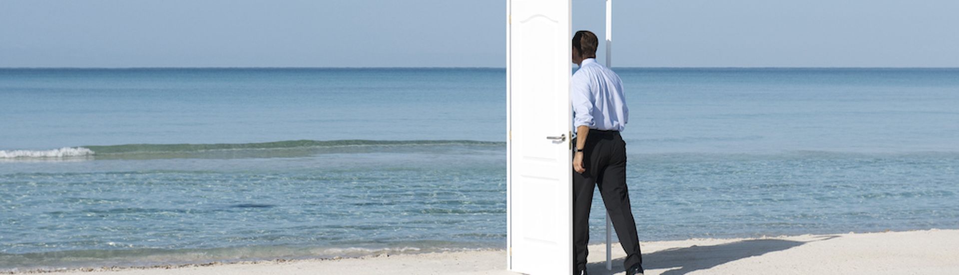 Man walking into open door on beach, rear view