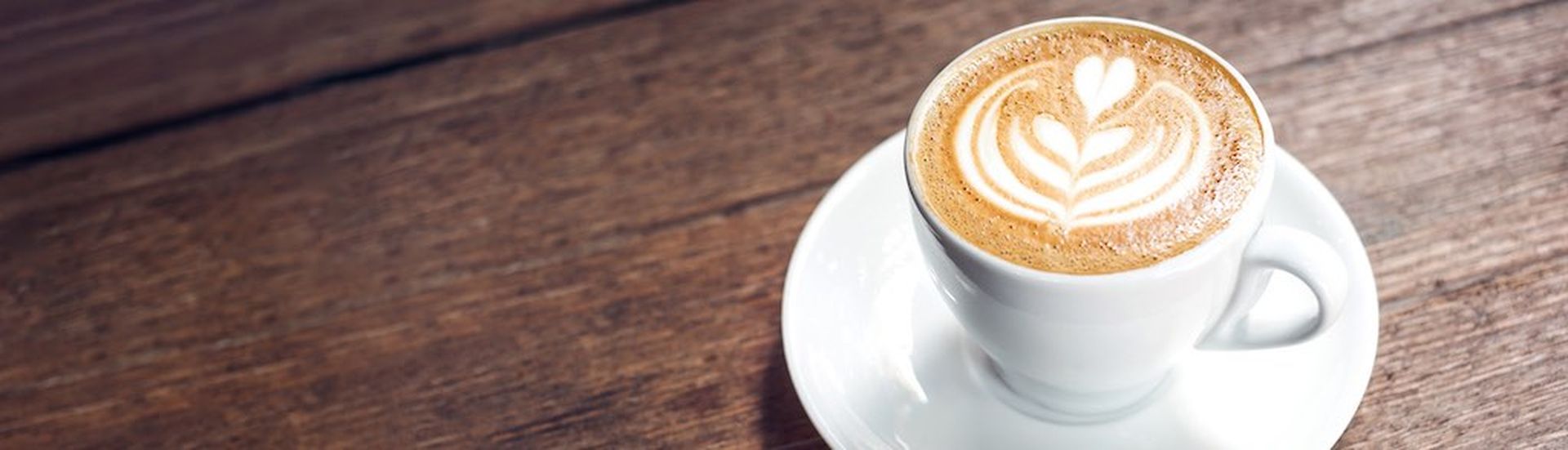 Close up hot cappuccino white coffee cup with heart shape latte art on dark brown old wood table at cafe,food and drink concept (Close up hot cappuccino white coffee cup with heart shape latte art on dark brown old wood table at cafe,food and drink co