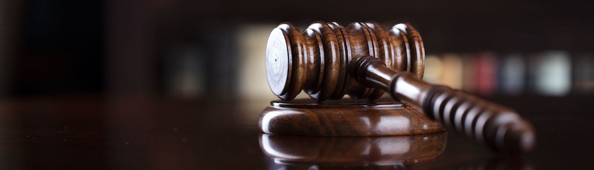 Judge‘s gavel on brown shining table and bookshelf background.