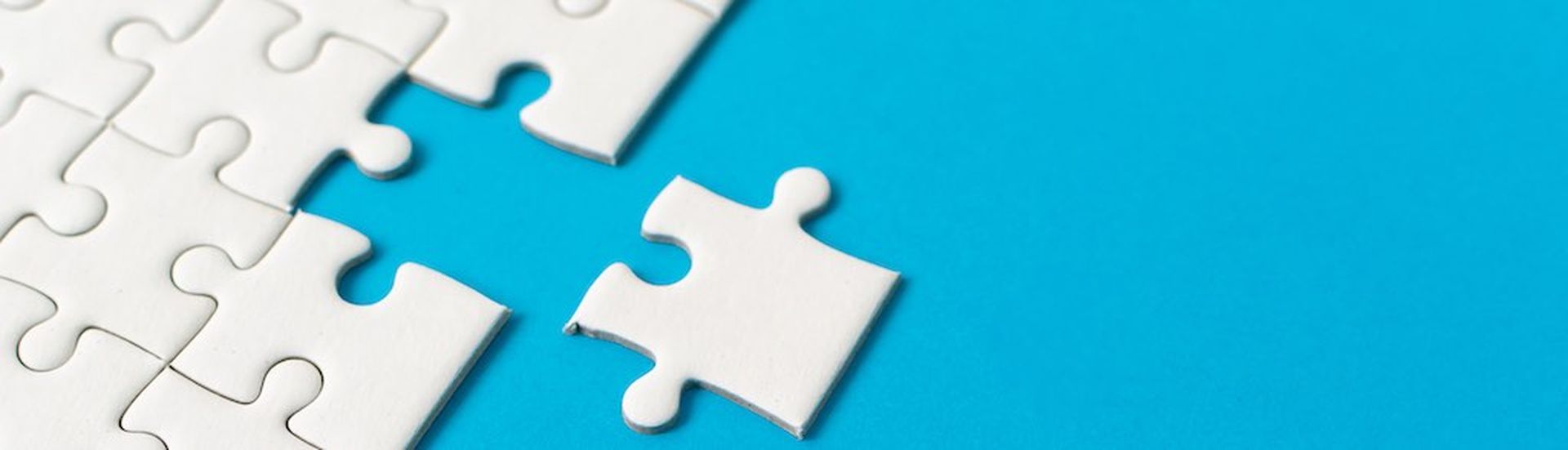 White jigsaw puzzle on blue background. Team business success partnership or teamwork.