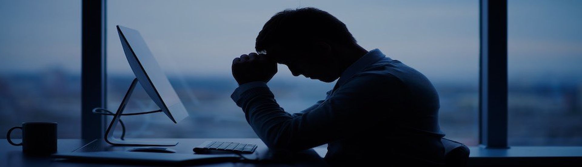 Tired or stressed businessman sitting in front of computer in office