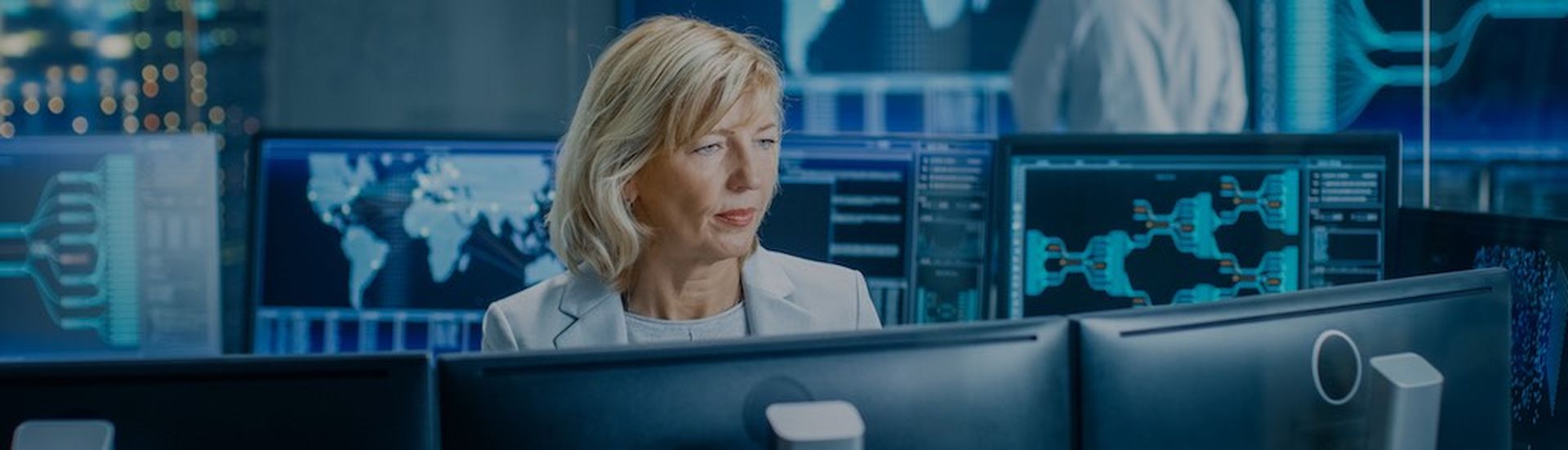 System Monitoring Room Professional Female Operator Observes Correct Functioning of the Facility. In the Background People Working with Interactive Map. (System Monitoring Room Professional Female Operator Observes Correct Functioning of the Facility.