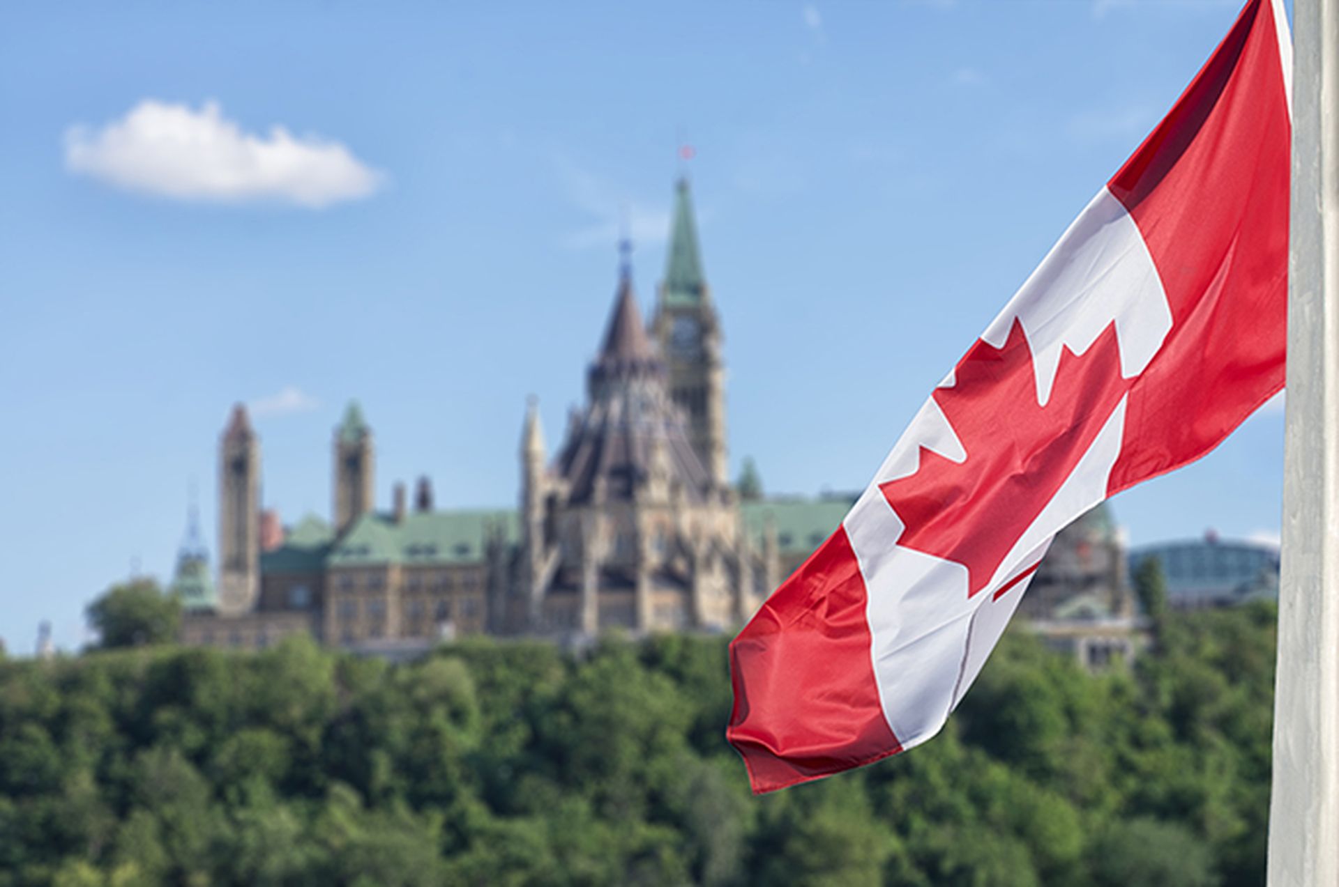 Canadian flag waving with Parliament Buildings hill and Library in the background