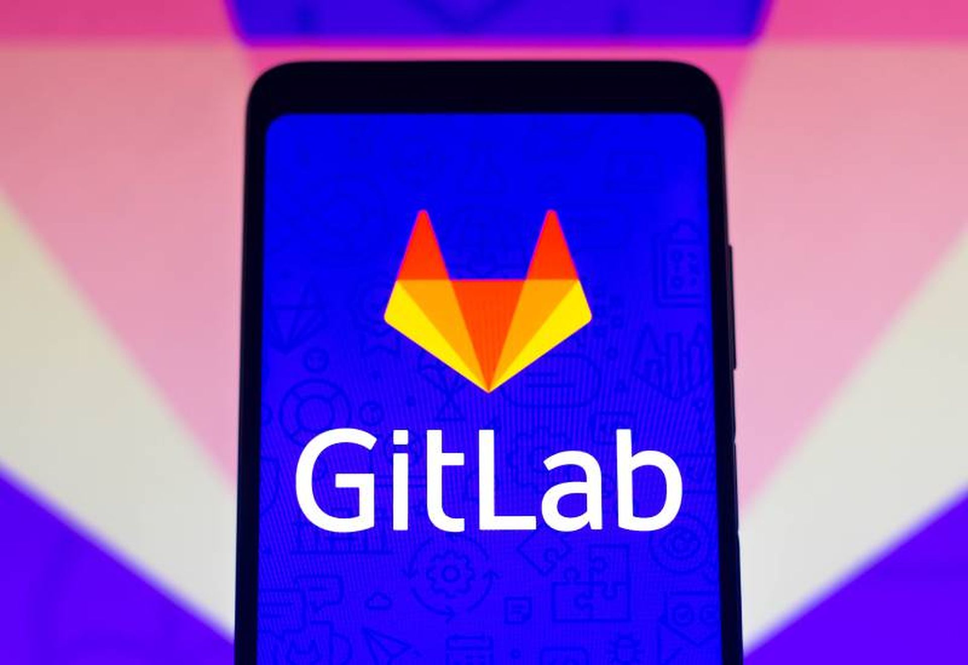 In this photo illustration the GitLab logo seen displayed on a smartphone and on the background.