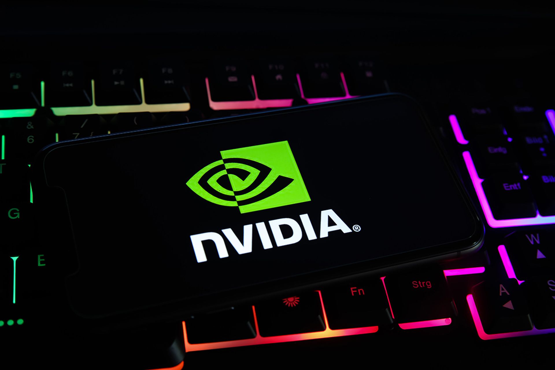 Closeup of mobile phone screen with logo lettering of nvidia corporation on computer keyboard