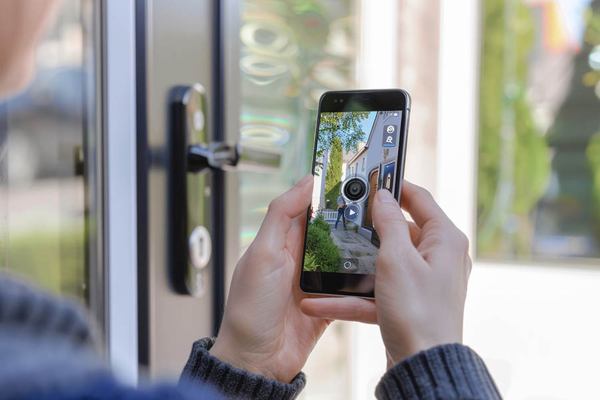 Hands holding a smartphone displaying the interface and video feed of a doorbell camera. the smart device showcases real-time surveillance footage, emphasizing modern home security solutions. essential technology for monitoring and ensuring safety at home.