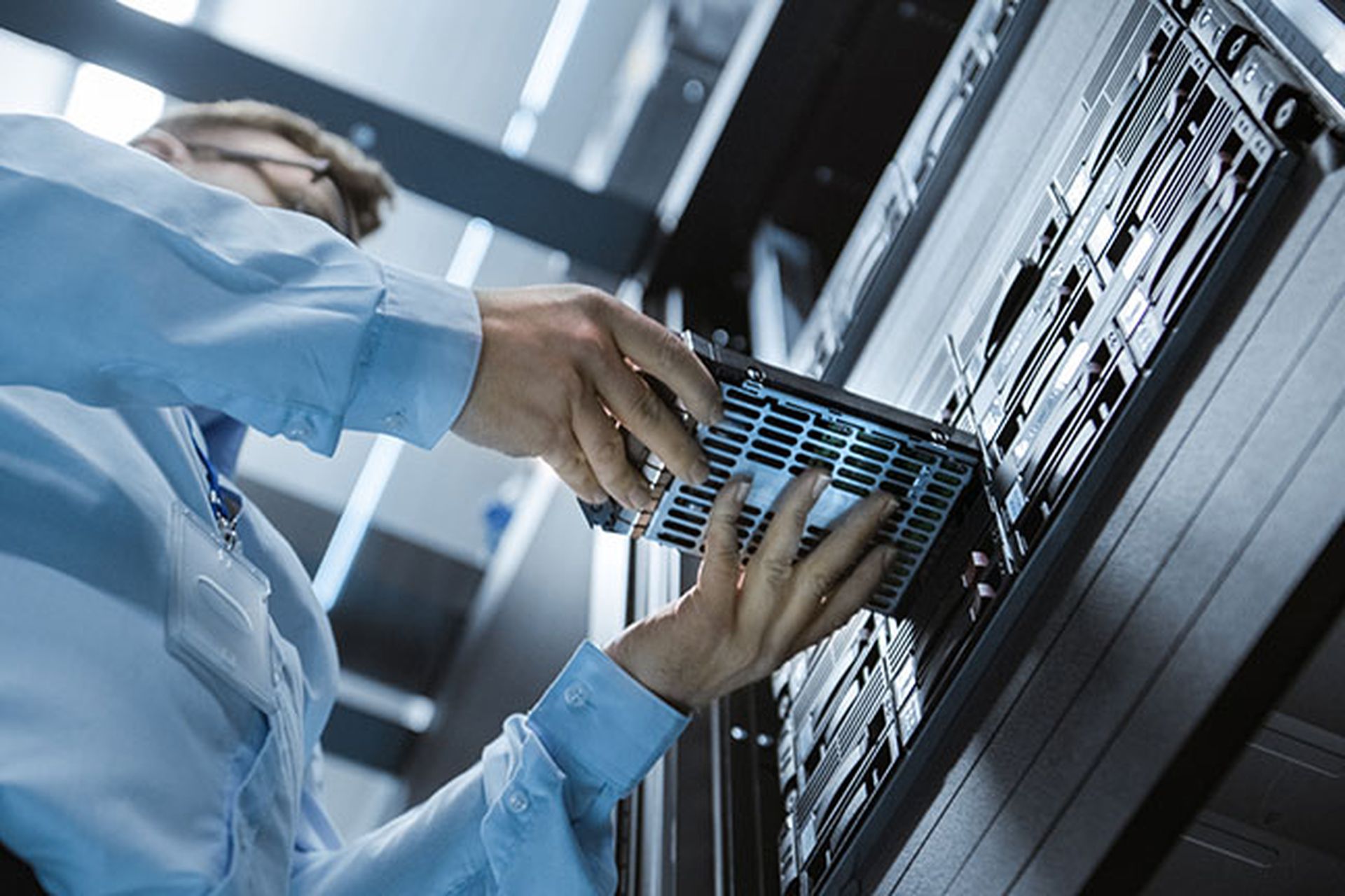 Low Angle Shot In Fully Working Data Center IT Engineer Installs Hard Drive into Server Rack. Detailed and Technically Accurate Footage.