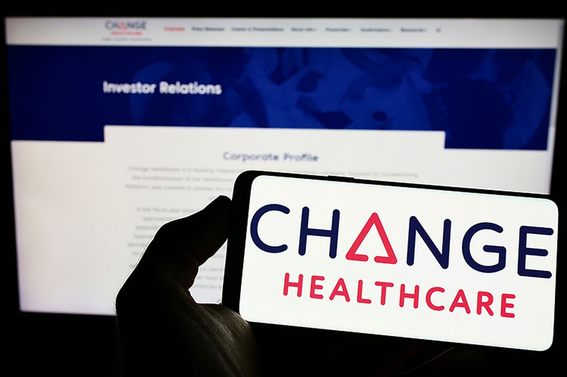 Person holding mobile phone with logo of American company Change Healthcare Inc. on screen in front of business web page.