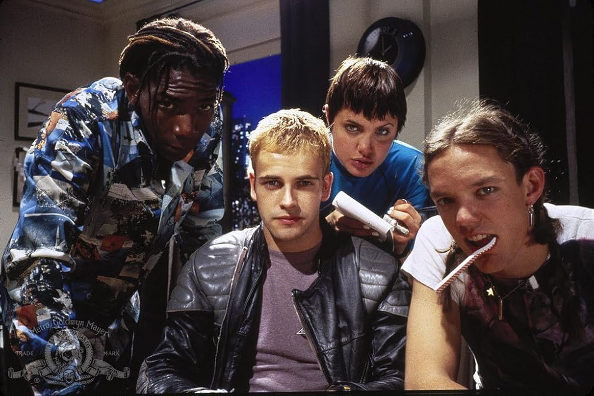 Four hackers gather around a computer screen in a still from the movie "Hackers."