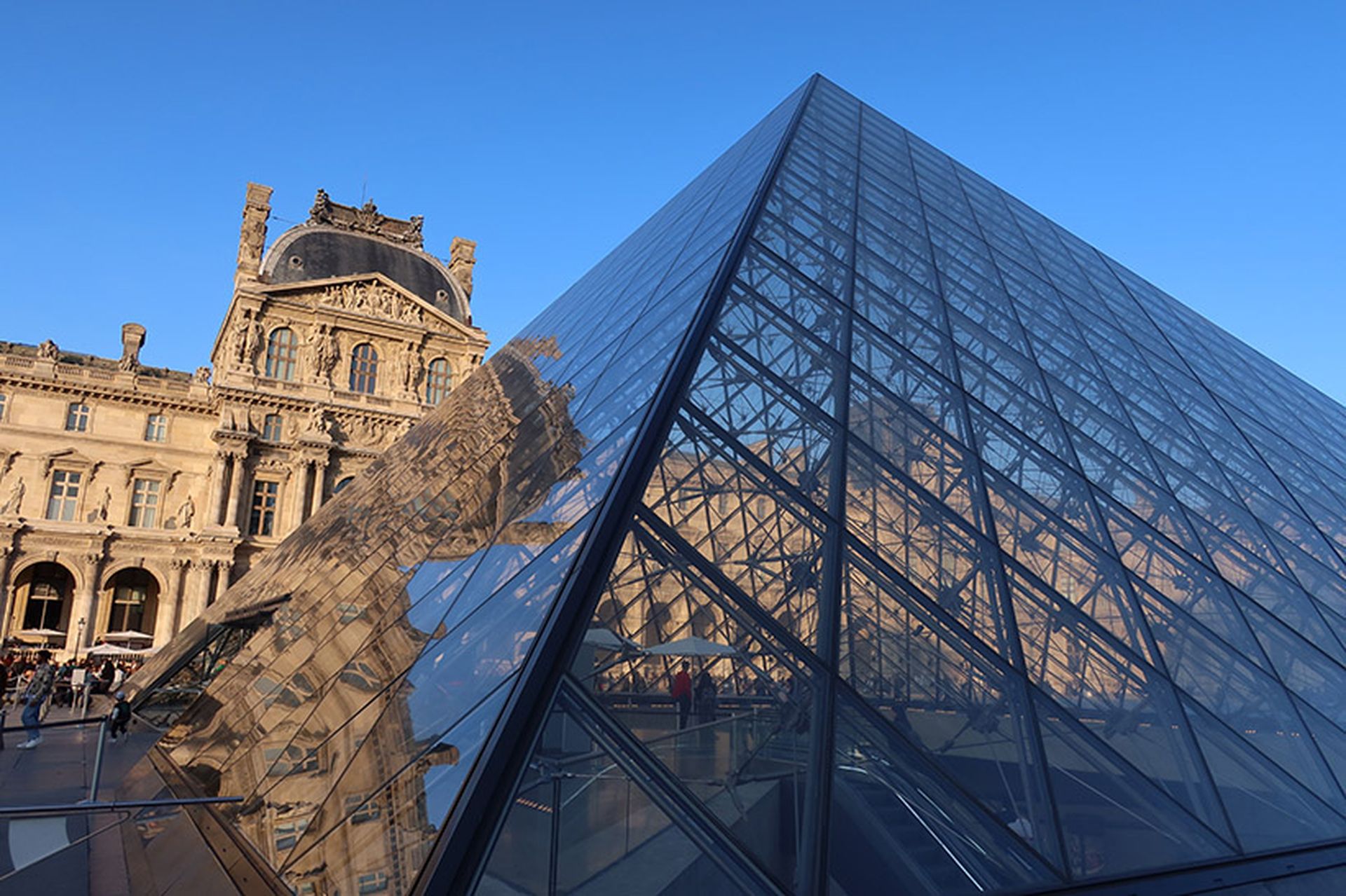 Palais / musée du Louvre à Paris, célèbre monument historique français, vue sur la pyramide en verre dans la cour Napoléon avec un reflet de la façade du pavillon Richelieu – octobre 2025 (France)