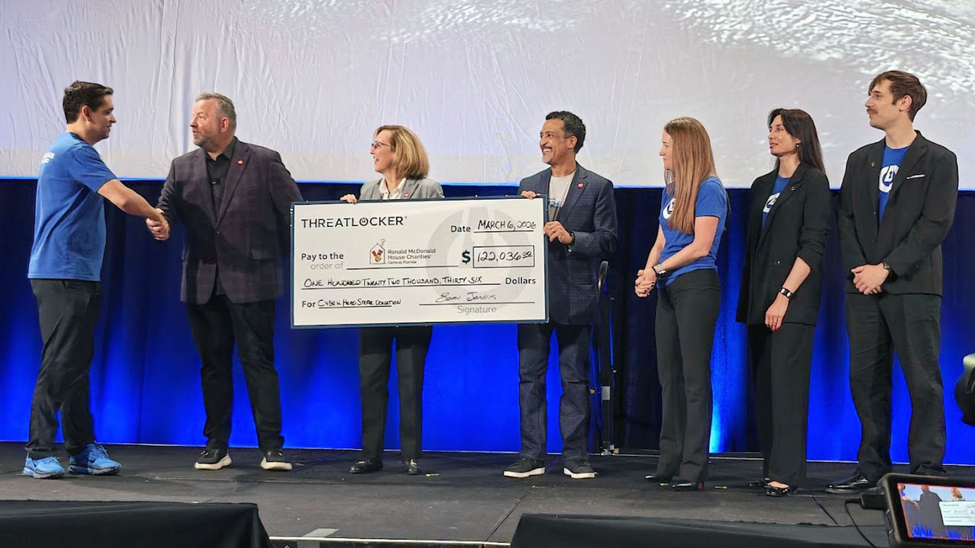 ThreatLocker CEO Danny Jenkins, at left, presents officials of Ronald McDonald House of Central Florida with a donation as ThreatLocker executives, including COO Sami Jenkins, third from right, look on at the Zero Trust World conference in Orlando, Florida, March 6, 2026. Credit: Paul Wagenseil/SC Media