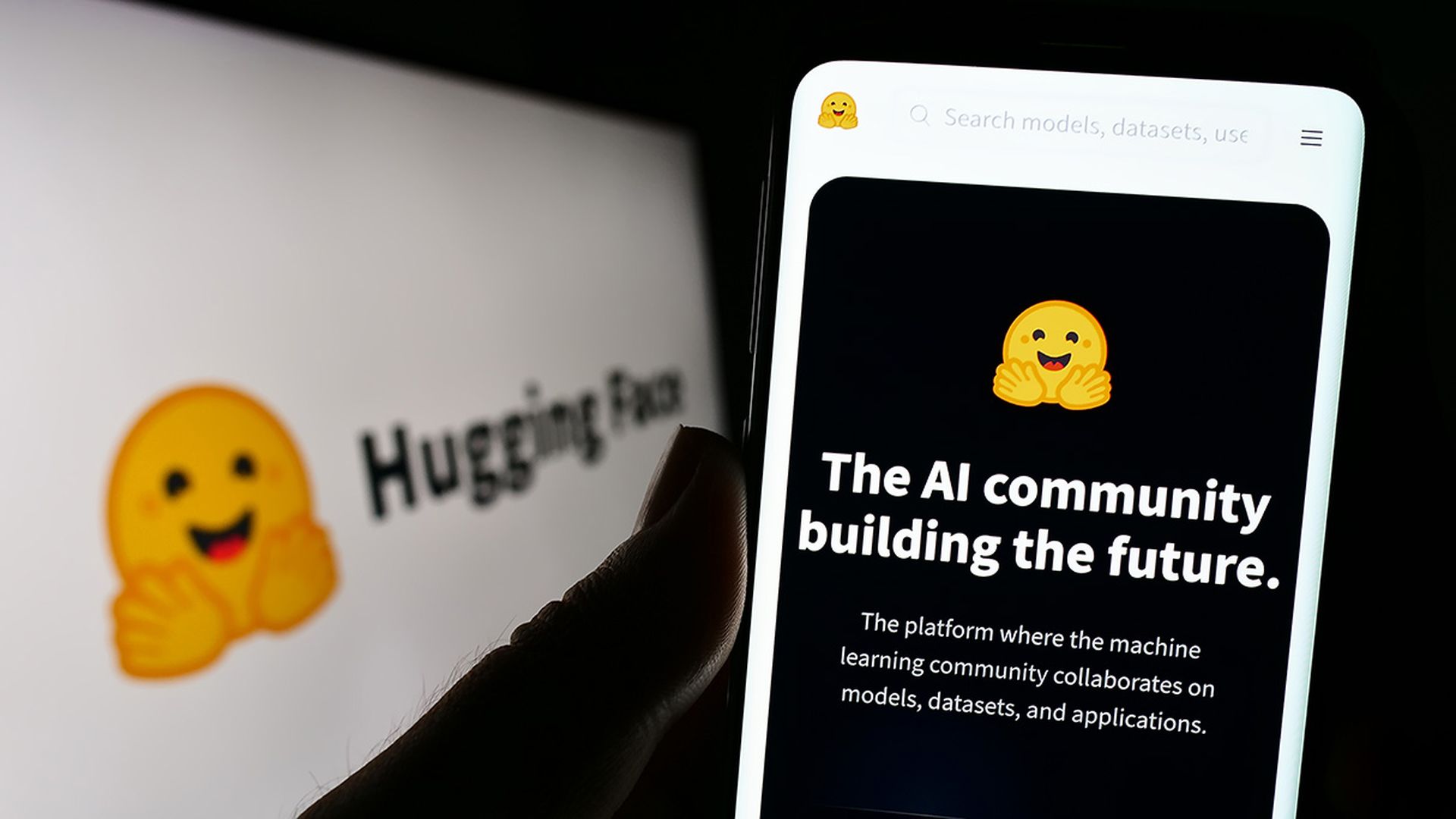 Person holding smartphone with webpage of artificial intelligence company Hugging Face Inc. on screen with logo. Focus on center of phone display.