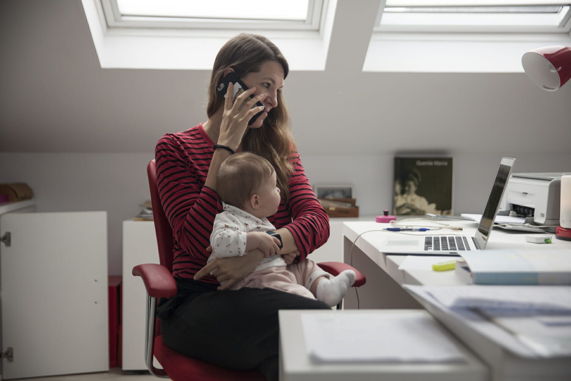 A women strives to work at home while holding her six-month-old daughter in Madrid, Spain. The European nation has had mixed results opening up following several months in lockdown because of the pandemic. (Photo by Miguel Pereira/Getty Images)
