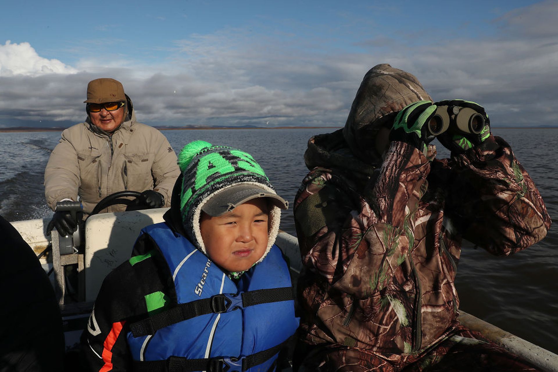 Left to right: Enoch Adams, Lukas Adams and his wife Charlene Adams hunt for caribou from a boat on Sept. 10, 2019, in Kivalina, Alaska. (Photo by Joe Raedle/Getty Images)