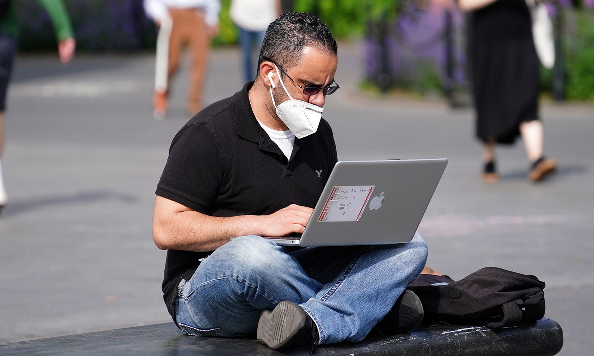 A man wearing a protective mask uses a laptop in Washington Square Park during the coronavirus pandemic on May 27, 2020, in New York City. (Photo by Cindy Ord/Getty Images)