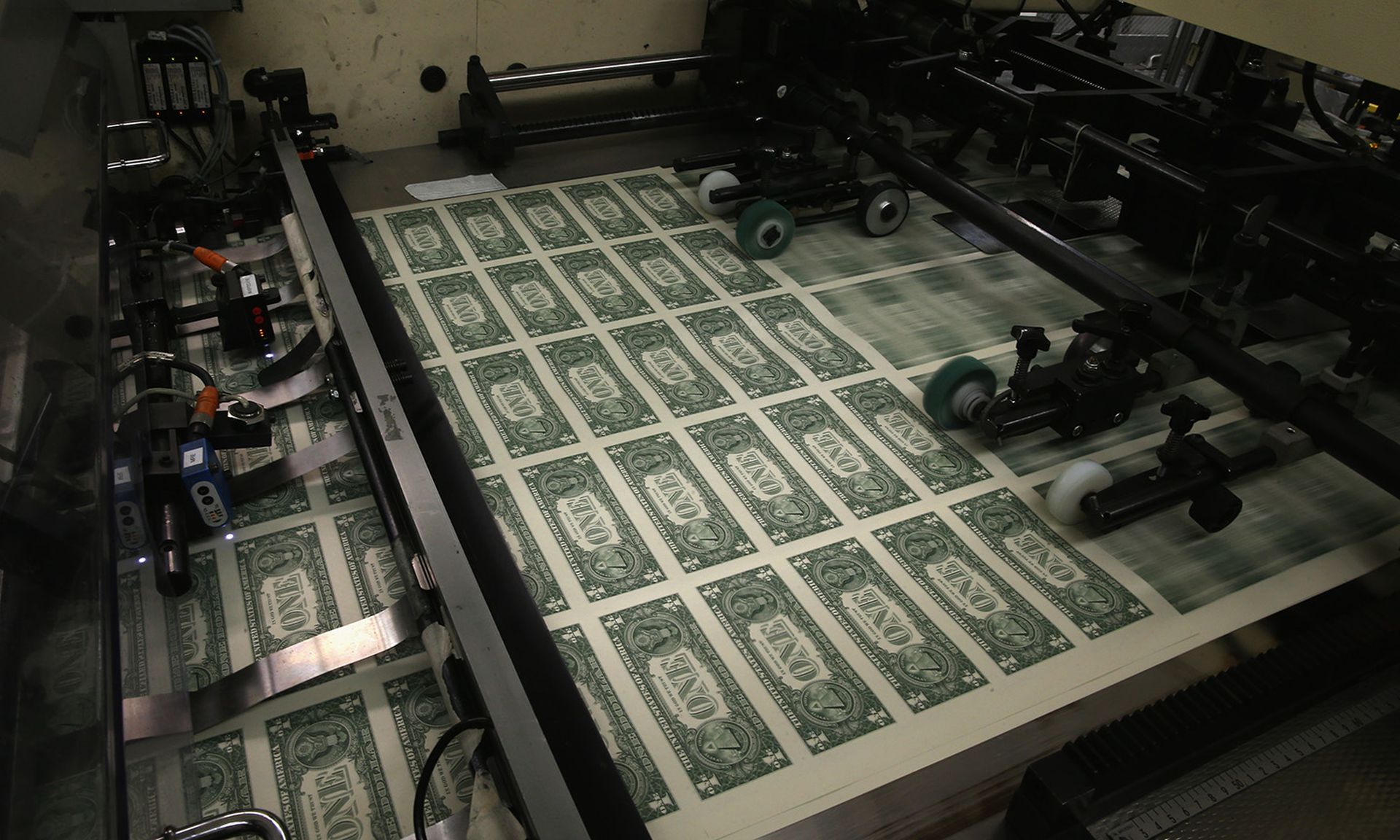 Sheets of one dollar bills run through the printing press at the Bureau of Engraving and Printing on March 24, 2015, in Washington. It costs financial services firms $2.1 million on average to recover from a ransomware attack, according to a new Sophos report. (Photo by Mark Wilson/Getty Images)
