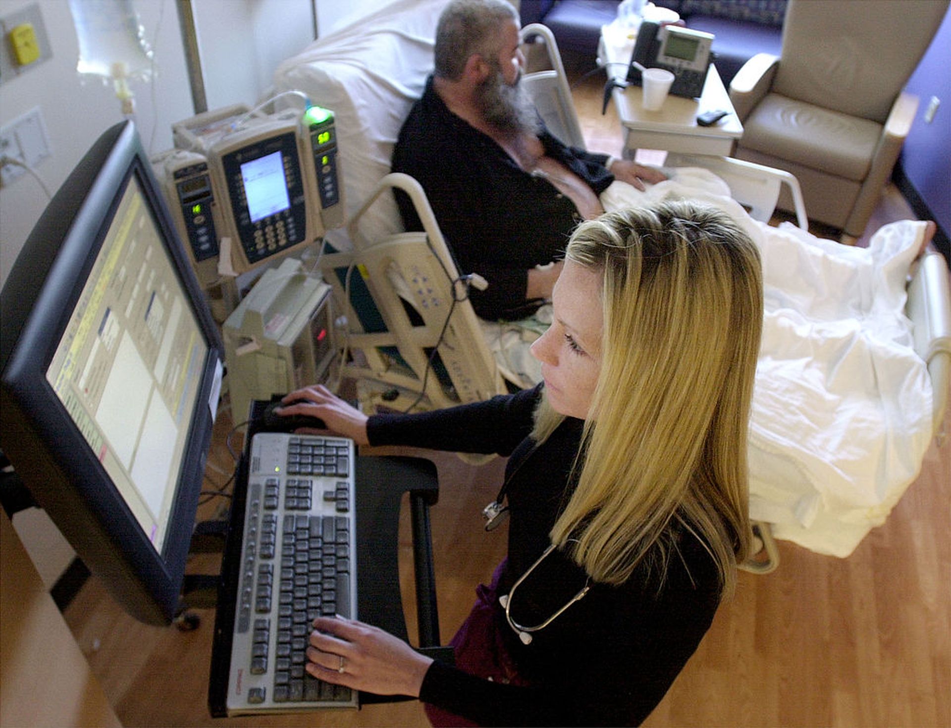 Jennifer Castagnier, R.N., works on a bedside workstation of the Pyxis Medstation System as patient Philipp Kohlbacher rests at the Indiana Heart Hospital April 1, 2003, in Indianapolis. (Photo by Mike Simons/Getty Images)