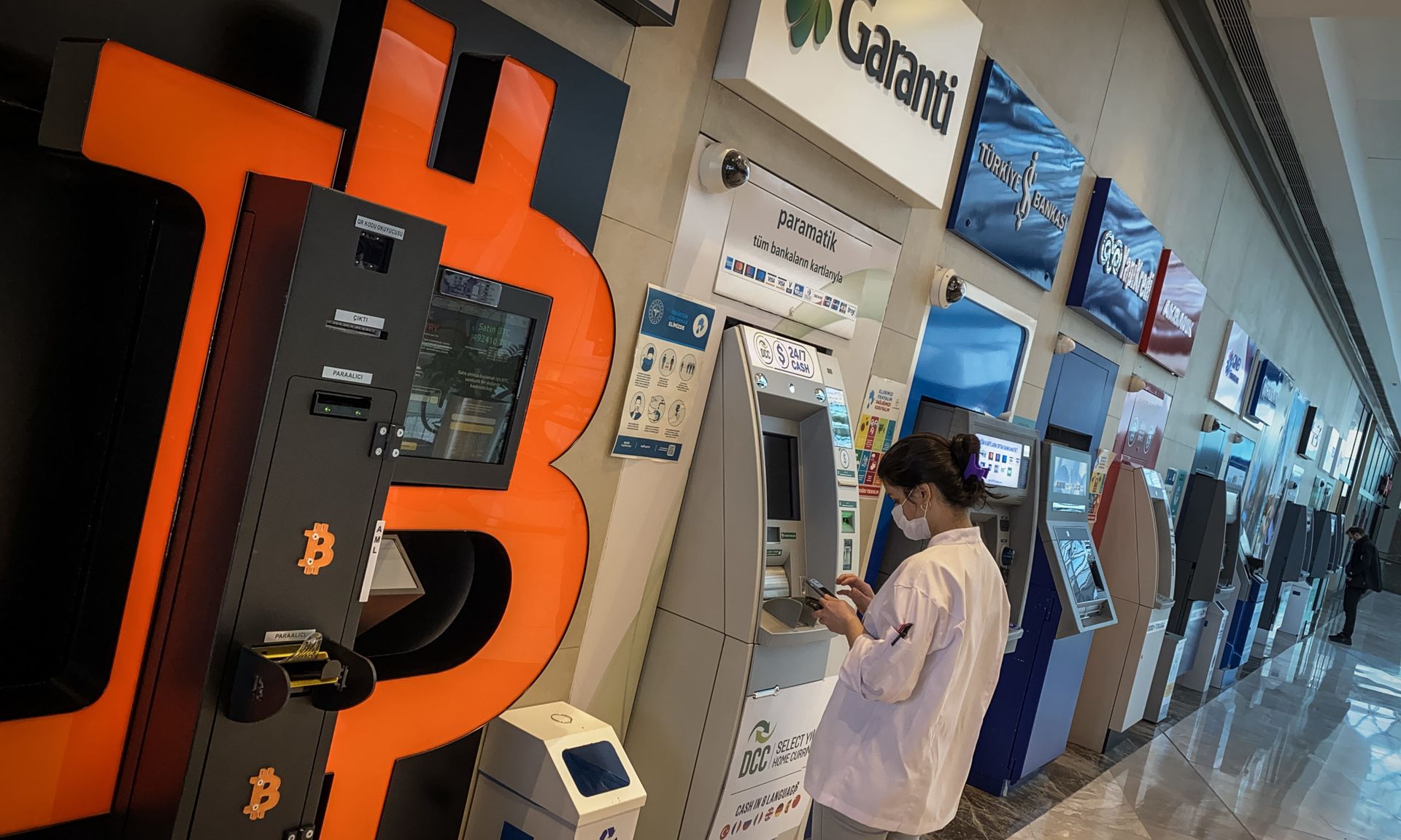 ISTANBUL, TURKEY &#8211; APRIL 16: A woman uses a bank ATM next to a Bitcoin ATM machine at a shopping mall  on April 16, 2021 in Istanbul, Turkey. Turkey&#8217;s Central Bank announced a ban on the use of cryptocurrencies and crypto assets for purchases, directly or indirectly to pay for goods or services. The announcement comes as Turkey&#8217;s ...