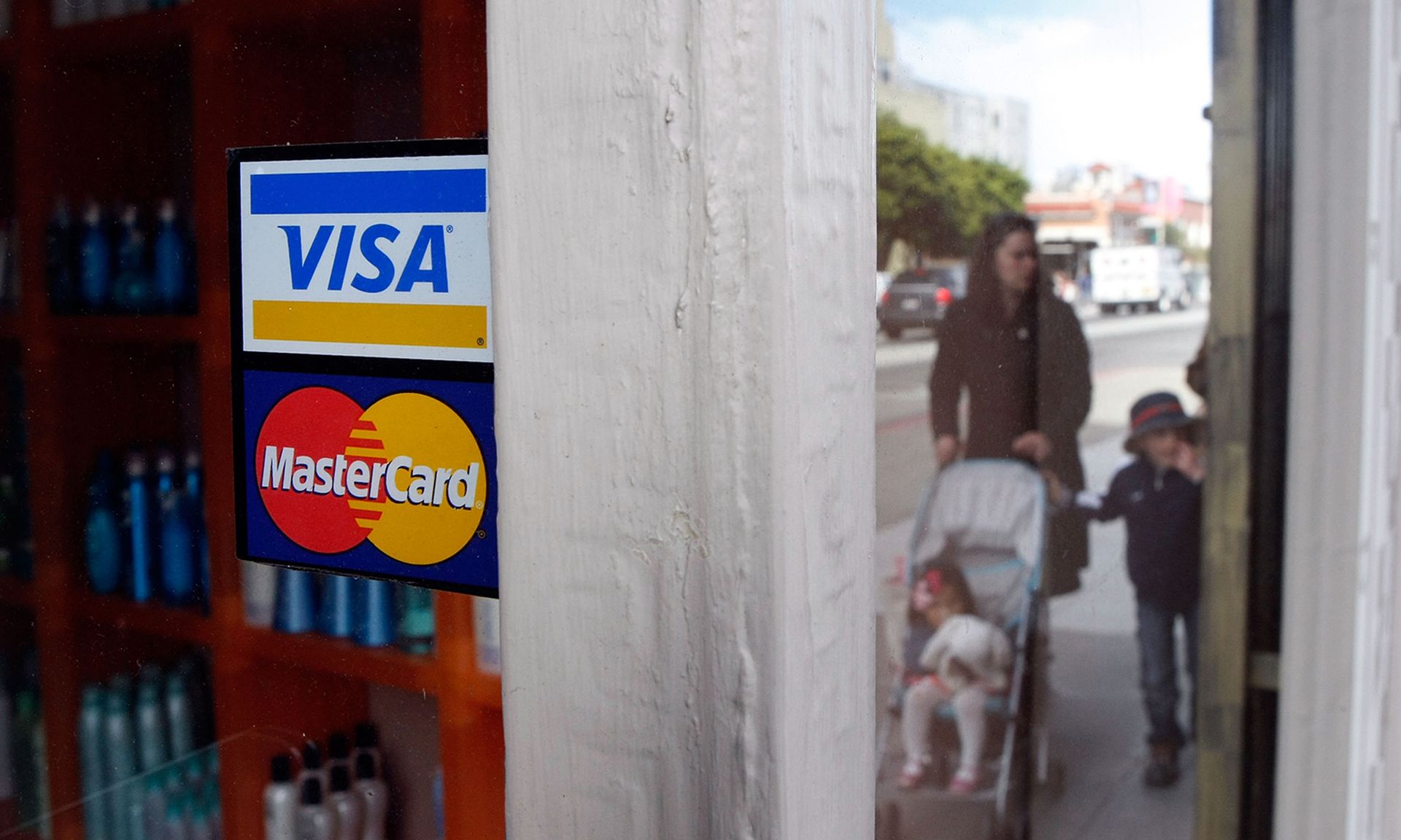 People walk by a window sticker advertising Visa and Mastercard credit cards Feb. 25, 2008, in San Francisco. (Justin Sullivan/Getty Images)