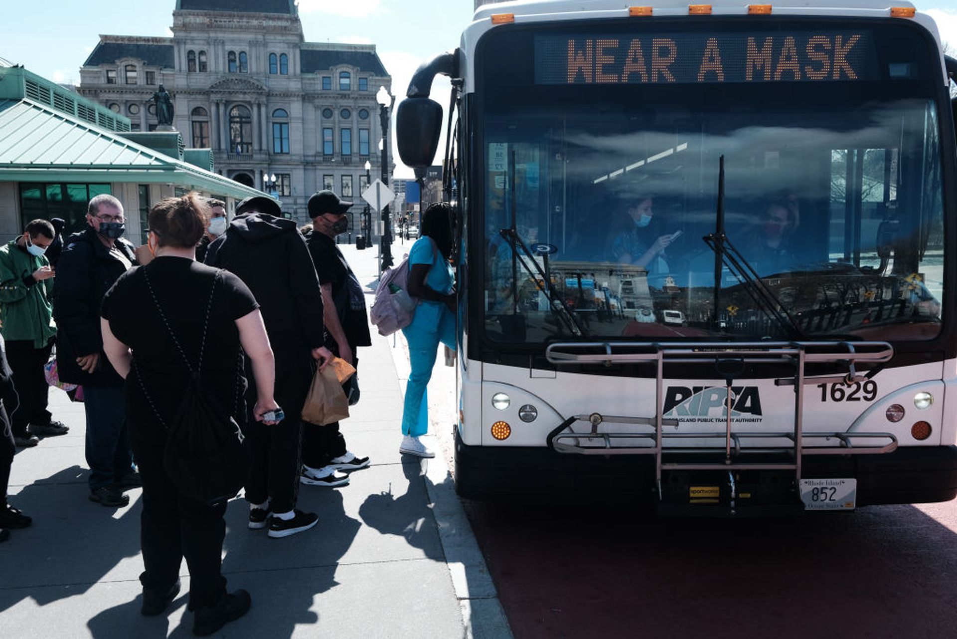 People board a bus at a stop on April 8, 2021, in Providence, R.I. An ongoing investigation into the public transit authority reveals new details, including that its former health plan administrator has been added to the review. (Photo by Spencer Platt/Getty Images)