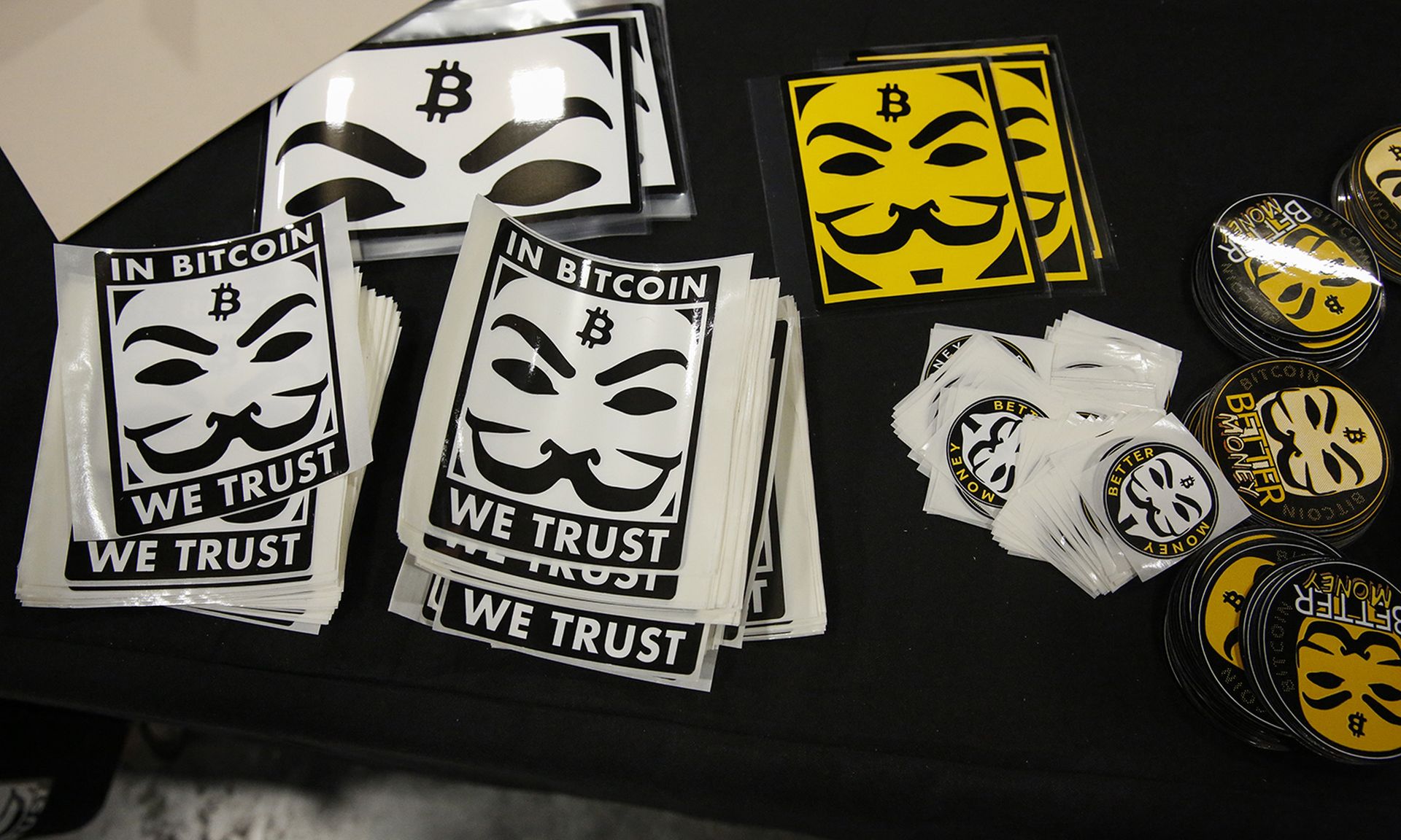 Chainalysis announced Wednesday the launch of a service to recover stolen cryptocurrency. Pictured: Stickers depicting Guy Fawkes masks (Anonymous mask) and the bitcoin logo are seen at a stand in the exhibition hall during the Bitcoin 2022 Conference at Miami Beach Convention Center on April 8, 2022, in Miami. (Photo by Marco Bello/Getty Images)