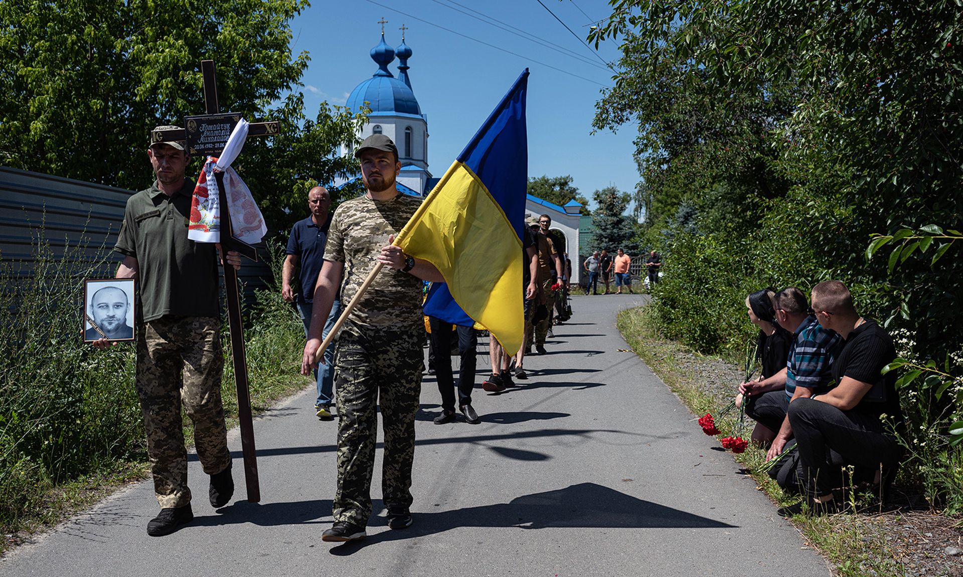 A leading financial technology analyst says every organization needs to be prepared for a cyber incident related to the Russia-Ukraine war. Pictured: People kneel as the funeral procession for Anatolii Potaichuk passes by on July 2, 2022, in Babyntsi, Ukraine. (Photo by Alexey Furman/Getty Images)