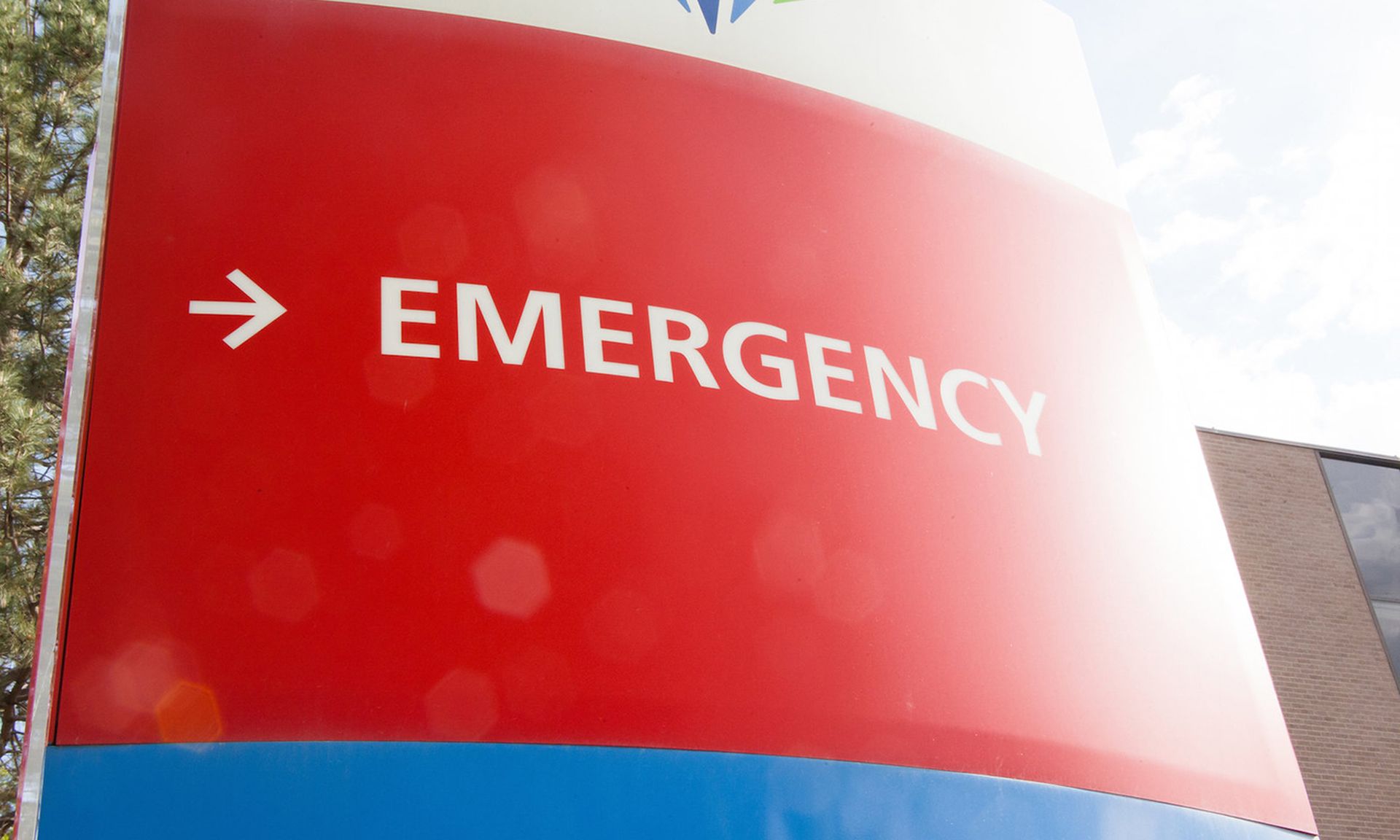 A red sign directing visitors to a hospital emergency room is seen.