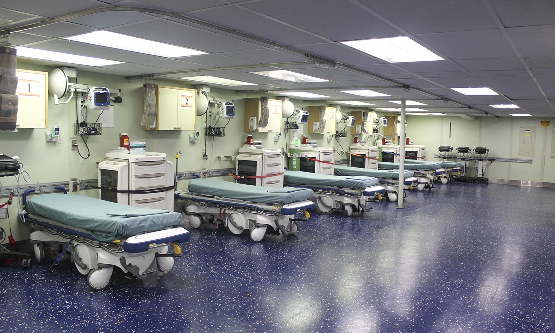A row of hospital beds and medical equipment are seen in an operating room.