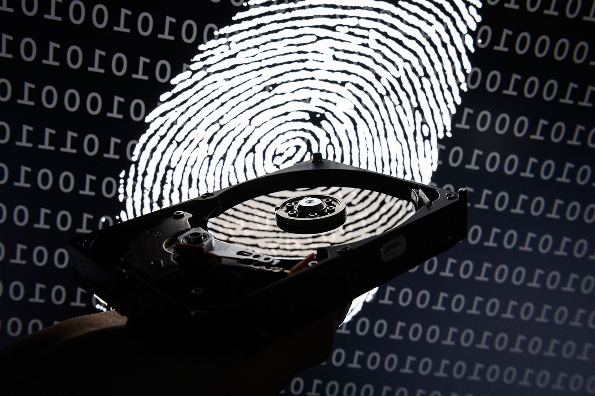 A hard drive is seen in the light of a projection of a thumbprint.